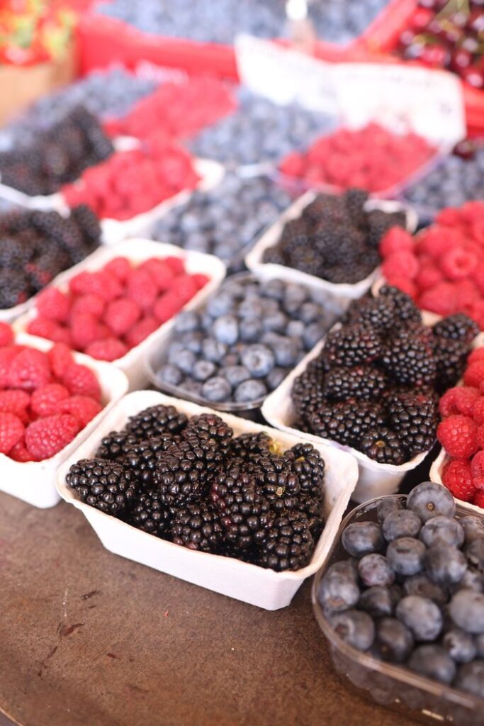 Vibrant display of fresh raspberries, blueberries, and blackberries at a local farmers market.